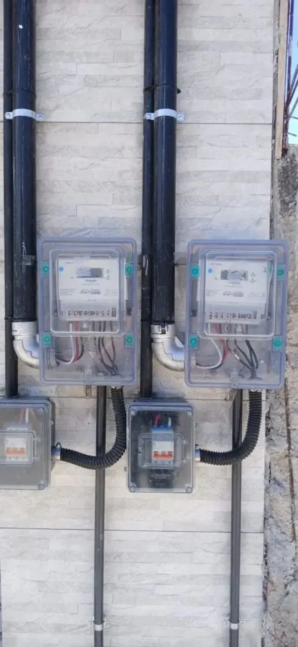 Medidores em caixas de proteção transparentes instalados na fachada de uma residência, imagem ilustrativa